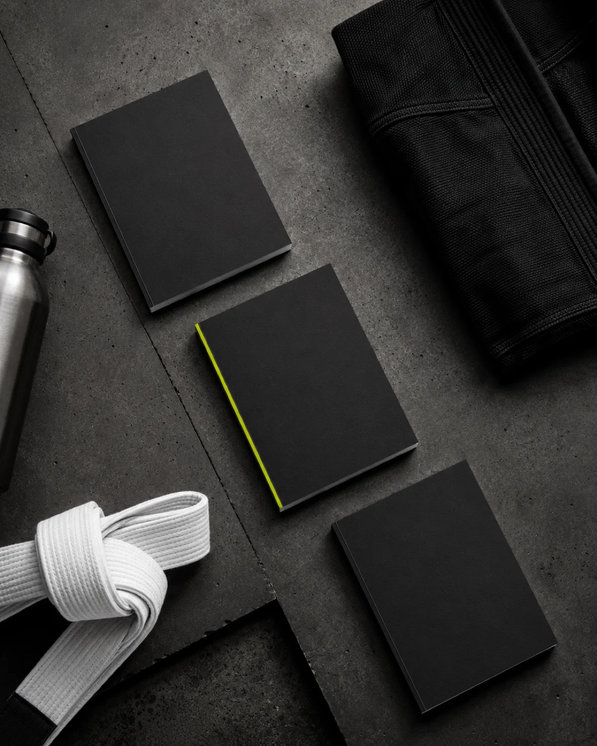 Guia em layout flat-lay sobre concreto com kimono preto e faixa branca